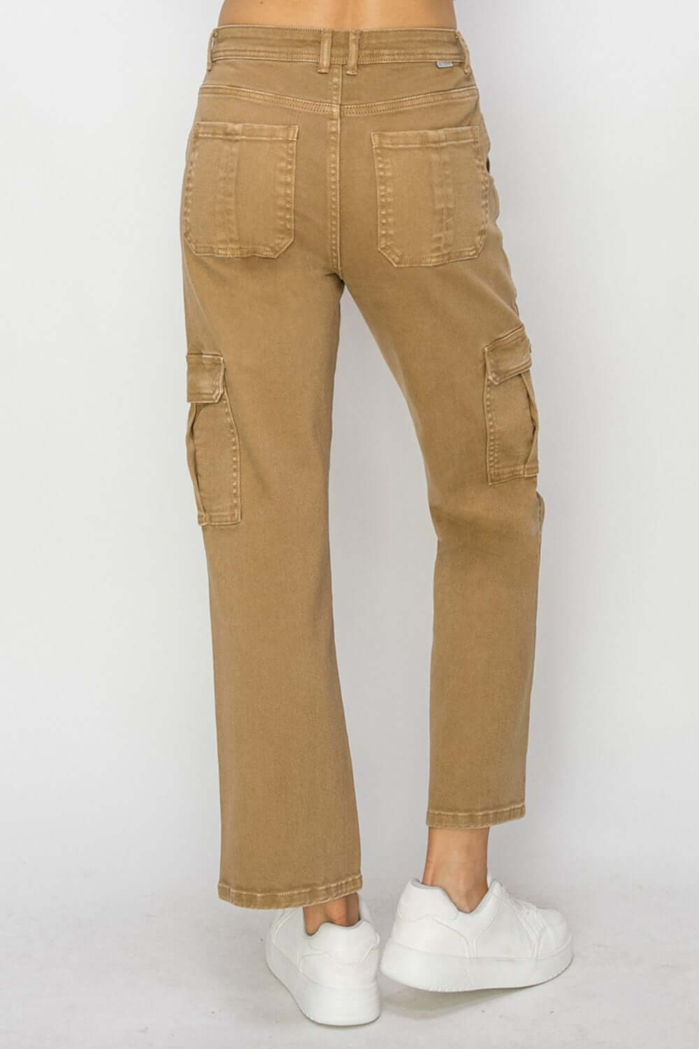 Back view of high-rise petite cargo jeans with utilitarian pockets in a rugged khaki color, paired with white sneakers. Risen Jeans.