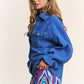 Woman wearing a stylish J.NNA snap-down long sleeve denim shacket over a colorful geometric skirt.