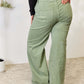 Woman modeling Risen Raw Hem Wide-Leg Jeans in sage green, showcasing high-waisted fit and trendy wide-leg design with back pocket details.