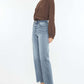 Woman wearing Kancan High Rise Slim Wide Leg Jeans in light wash with a brown blouse and tan shoes.