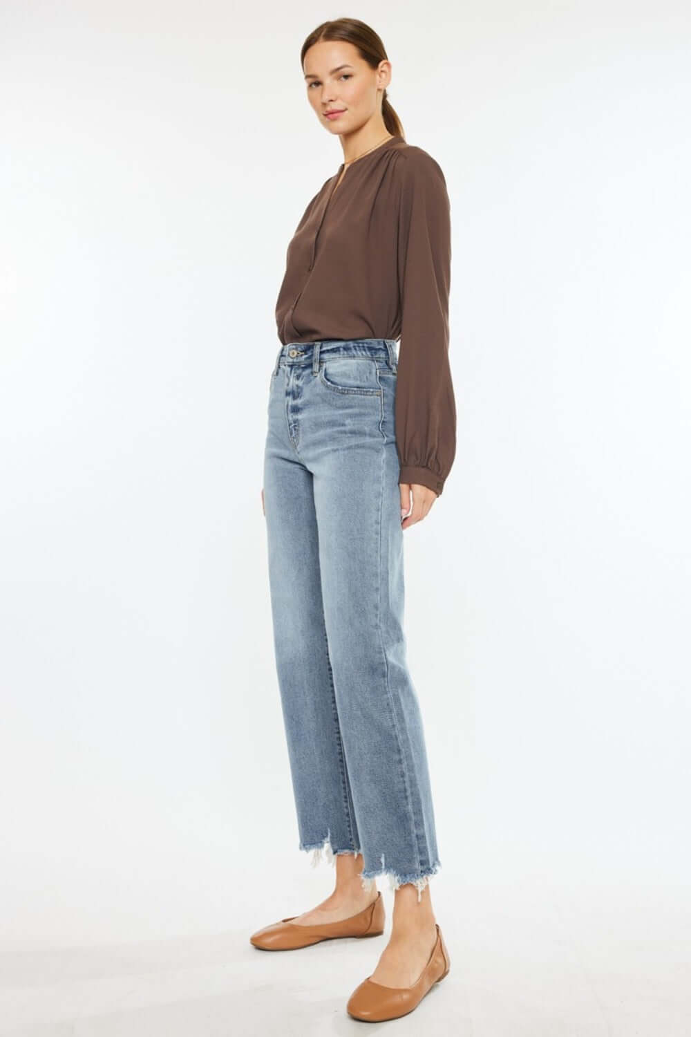 Woman wearing Kancan High Rise Slim Wide Leg Jeans in light wash with a brown blouse and tan shoes.