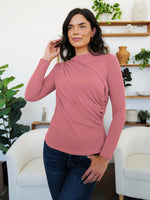 Woman wearing Dusty Pink FAM-FAM Ruched Mock Neck Long Sleeve T-Shirt indoors, styled with plants in the background