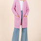 Stylish woman in a pink longline cardigan with pockets, paired with wide-leg jeans, perfect for any casual outfit.