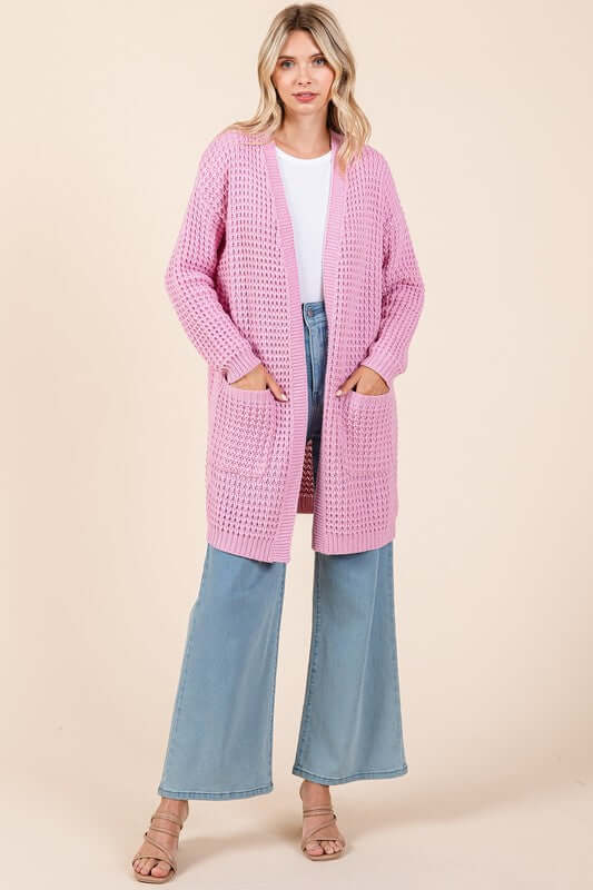 Stylish woman in a pink longline cardigan with pockets, paired with wide-leg jeans, perfect for any casual outfit.