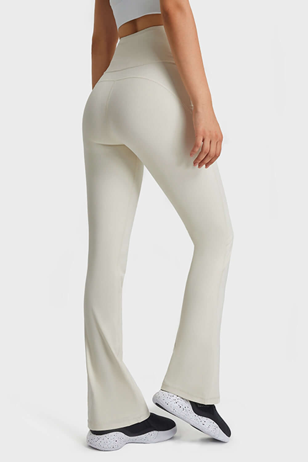 Model showcases Millennia Elastic Waist Flare Yoga Pants in cream, perfect for yoga and workouts with ultimate comfort and style.