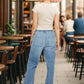 Woman wearing drawstring straight jeans with pockets, standing in outdoor cafe setting.