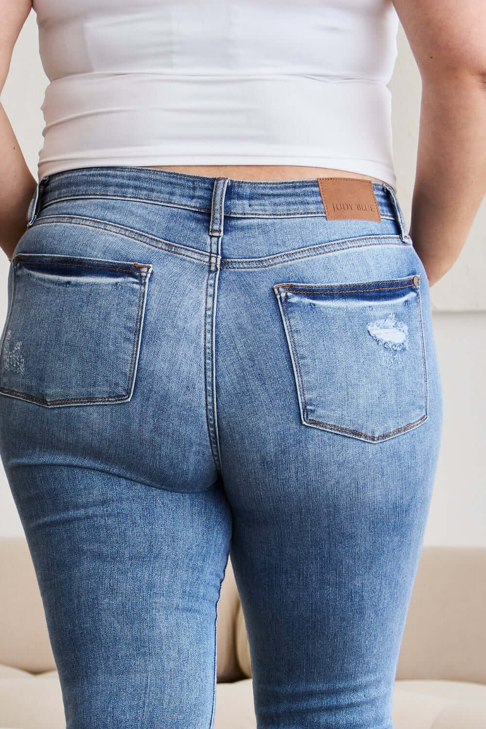 Back view of woman wearing Judy Blue release hem cropped bootcut jeans showcasing trendy and stylish denim design.