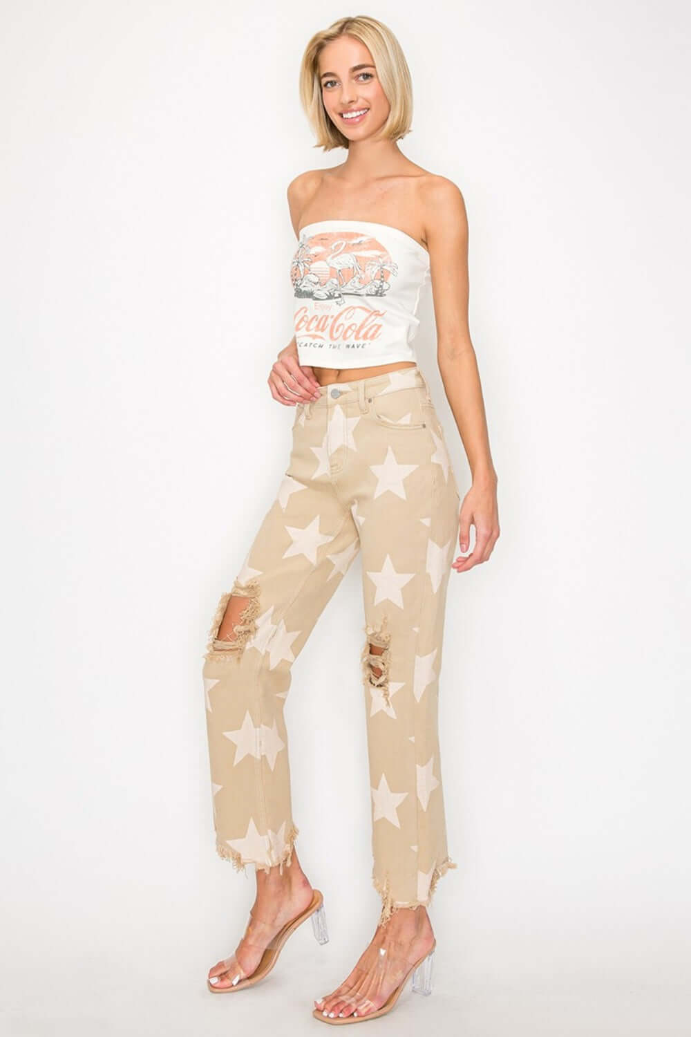 High rise star printed jeans with frayed hem styled with a casual top and clear heels for a trendy and edgy look.