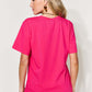 Woman wearing bright pink MAMA round neck short sleeve t-shirt, viewed from the back, paired with jeans.