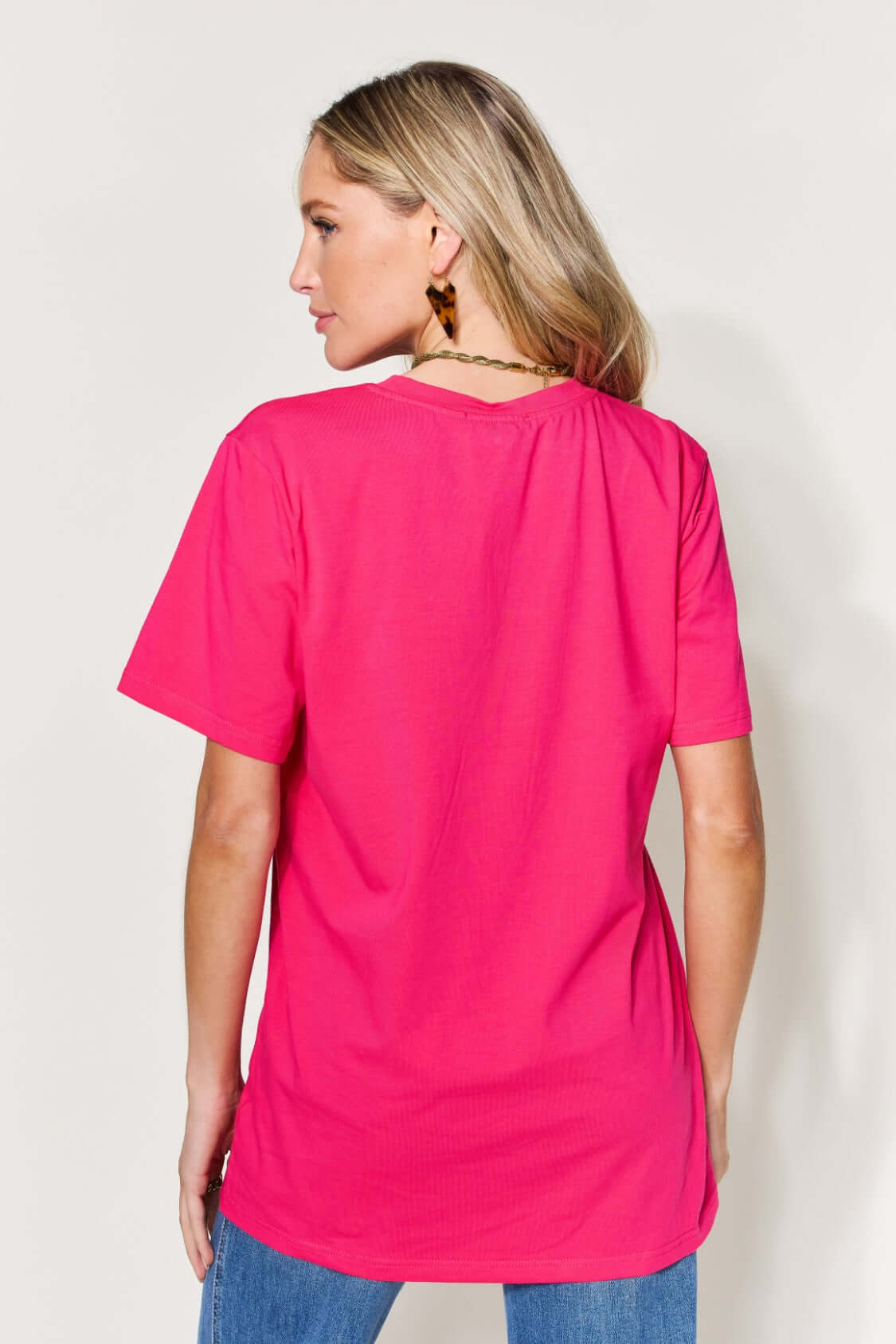 Woman wearing bright pink MAMA round neck short sleeve t-shirt, viewed from the back, paired with jeans.