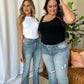 Two women wearing Judy Blue medium rise tummy control destroy flare jeans in a stylish indoor setting.