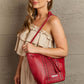 Woman with Nicole Lee USA Amy Studded Bucket Bag in red vegan leather, showing stud and zipper detailing on the front.