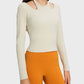 Model showcasing the Millennia Halter Neck Long Sleeve Sporty Top in cream with stylish cutouts and orange leggings.