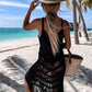 Woman in a black fringe cover-up and straw hat enjoying a beach view, perfect for a stylish poolside look.