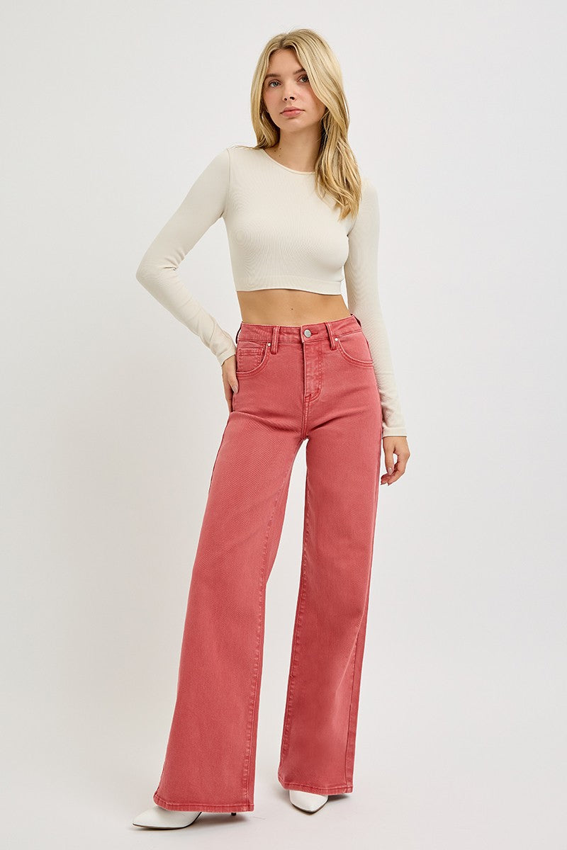 Woman wearing full size high rise tummy control wide leg jeans in rose color paired with a cream top.