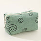 Fun green corduroy cosmetic pouch with smiley face design, perfect for organizing makeup essentials on the go.