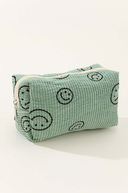 Fun green corduroy cosmetic pouch with smiley face design, perfect for organizing makeup essentials on the go.