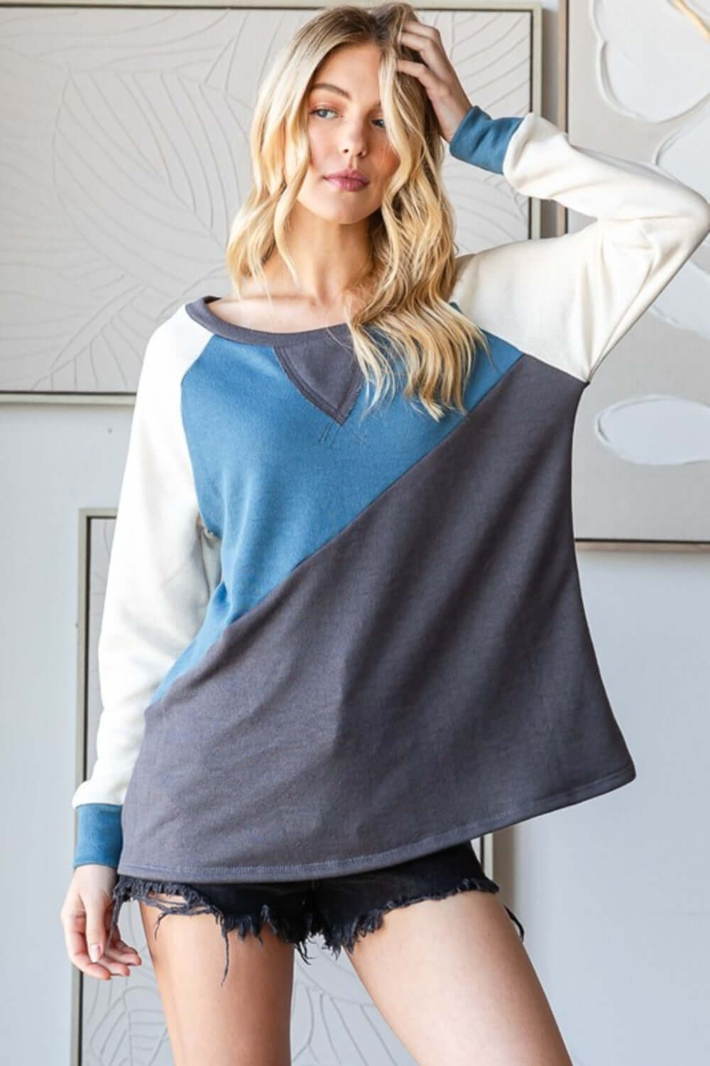 Woman wearing HOPELY color block long sleeve T-shirt in blue and gray, paired with denim shorts, casual fashion look.