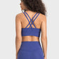 Back view of a woman in a blue crisscross active tank top, showcasing its stylish and breathable design.