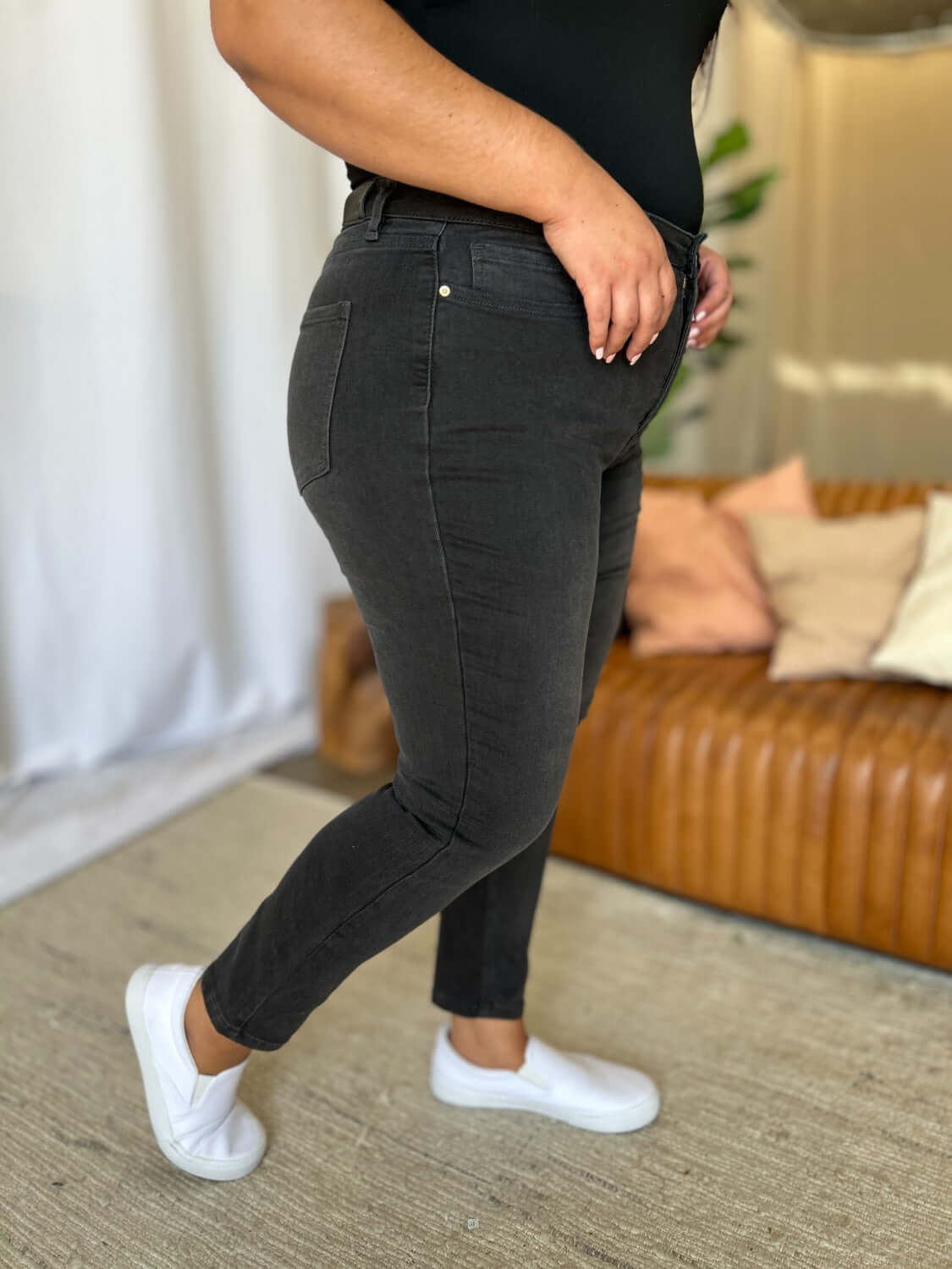 Person wearing RFM Full Size High Rise Tummy Control Skinny Jeans in a living room setting