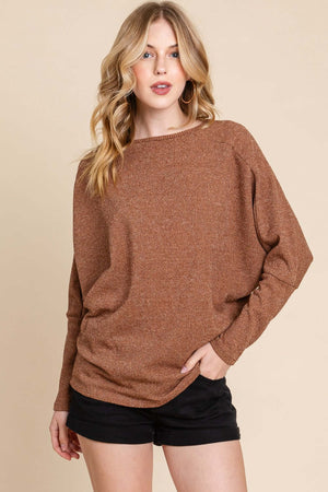 Woman wearing a brown drop shoulder long sleeve knit top, pairing casual style with black shorts.