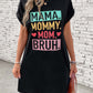 Woman wearing a black letter graphic short sleeve mini tee dress with "MAMA. MOMMY. MOM. BRUH." print, styled with accessories.