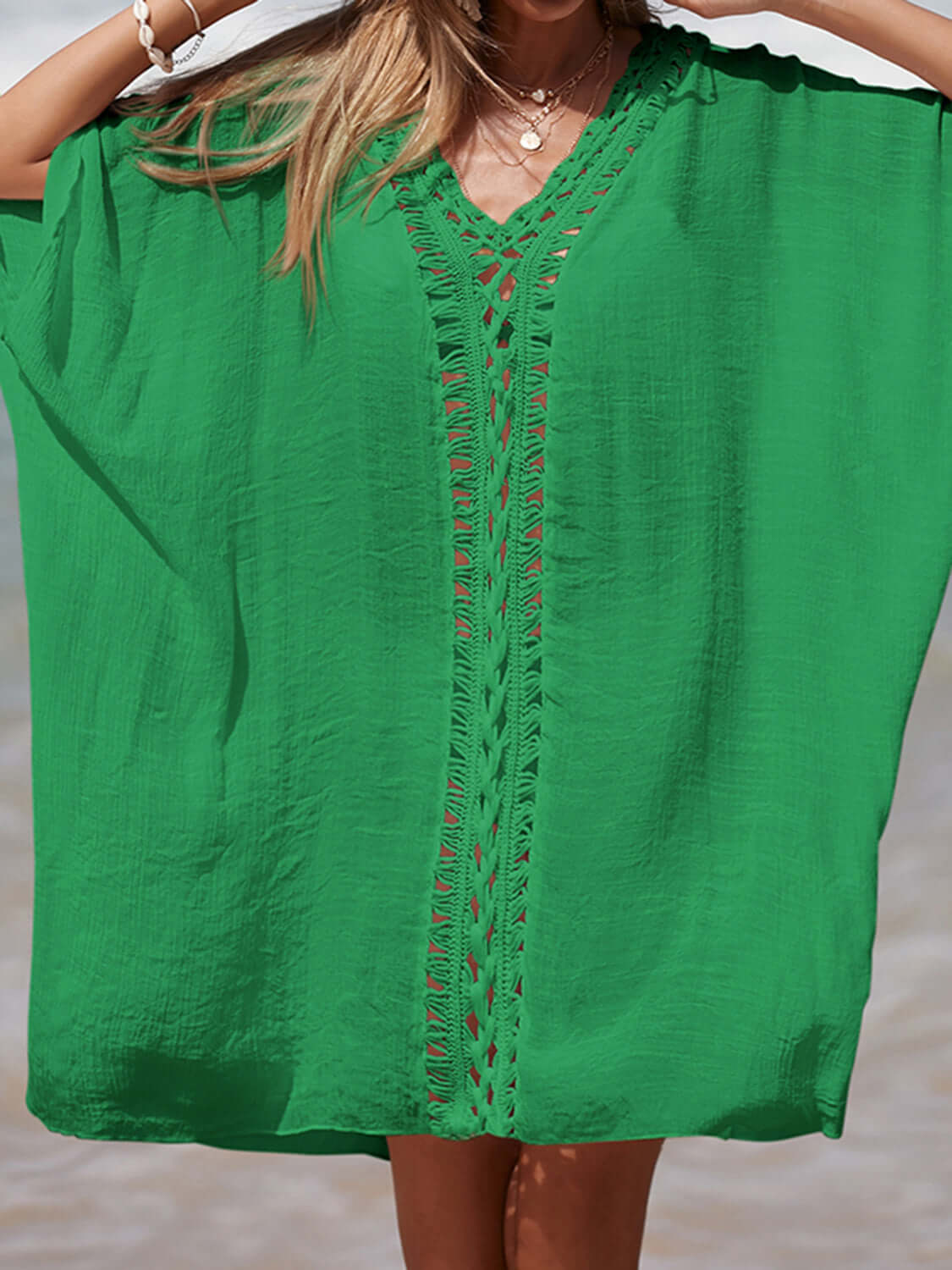 Woman wearing a green cutout V-neck three-quarter sleeve cover-up with openwork design on the beach.