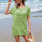 Woman in a green openwork cover-up and sunhat, enjoying the beach with waves in the background. Perfect summer style!