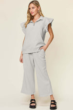 Woman wearing a Texture Ruffle Short Sleeve Top and Drawstring Wide Leg Pants Set in light gray with pockets, slightly stretchy fabric.