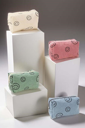 Colorful smiley face corduroy cosmetic pouches displayed on pedestals, perfect for organizing makeup essentials.