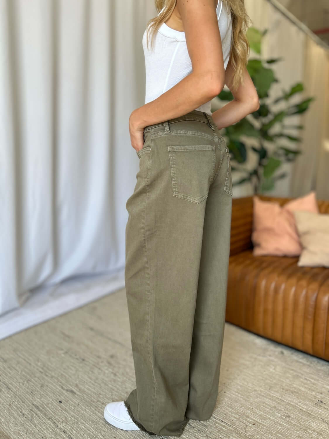 Woman posing in RFM High Rise Garment Dye Wide Leg Jeans with a relaxed fit, showcasing unique rich color against a stylish indoor backdrop.