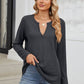 Woman wearing Bella Road waffle-knit notched long sleeve t-shirt in charcoal color styling with jeans on outdoor stairs.