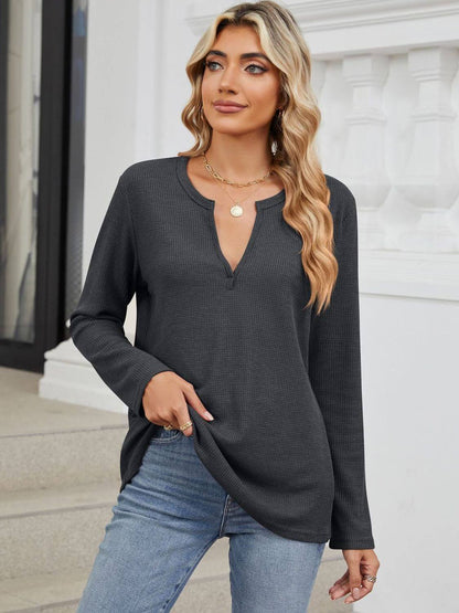 Woman wearing Bella Road waffle-knit notched long sleeve t-shirt in charcoal color styling with jeans on outdoor stairs.