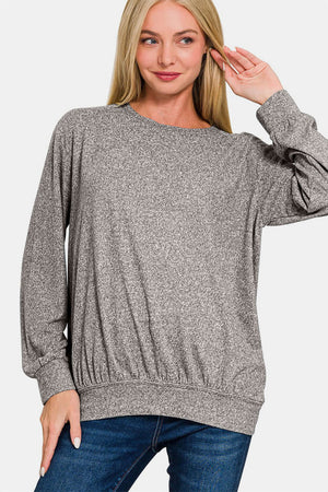 Woman wearing Zenana Full Size Melange Round Neck Top with jeans, showcasing comfort and style for versatile wardrobe options.