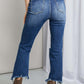 Woman wearing Frayed Hem Distressed Cropped Risen Jeans with boots, showcasing stylish raw hems and pockets for a casual look.