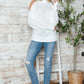 Woman wearing Bella Road Cable-Knit Cold Shoulder Turtleneck Sweater, styled with jeans and sneakers for a cozy-chic look.