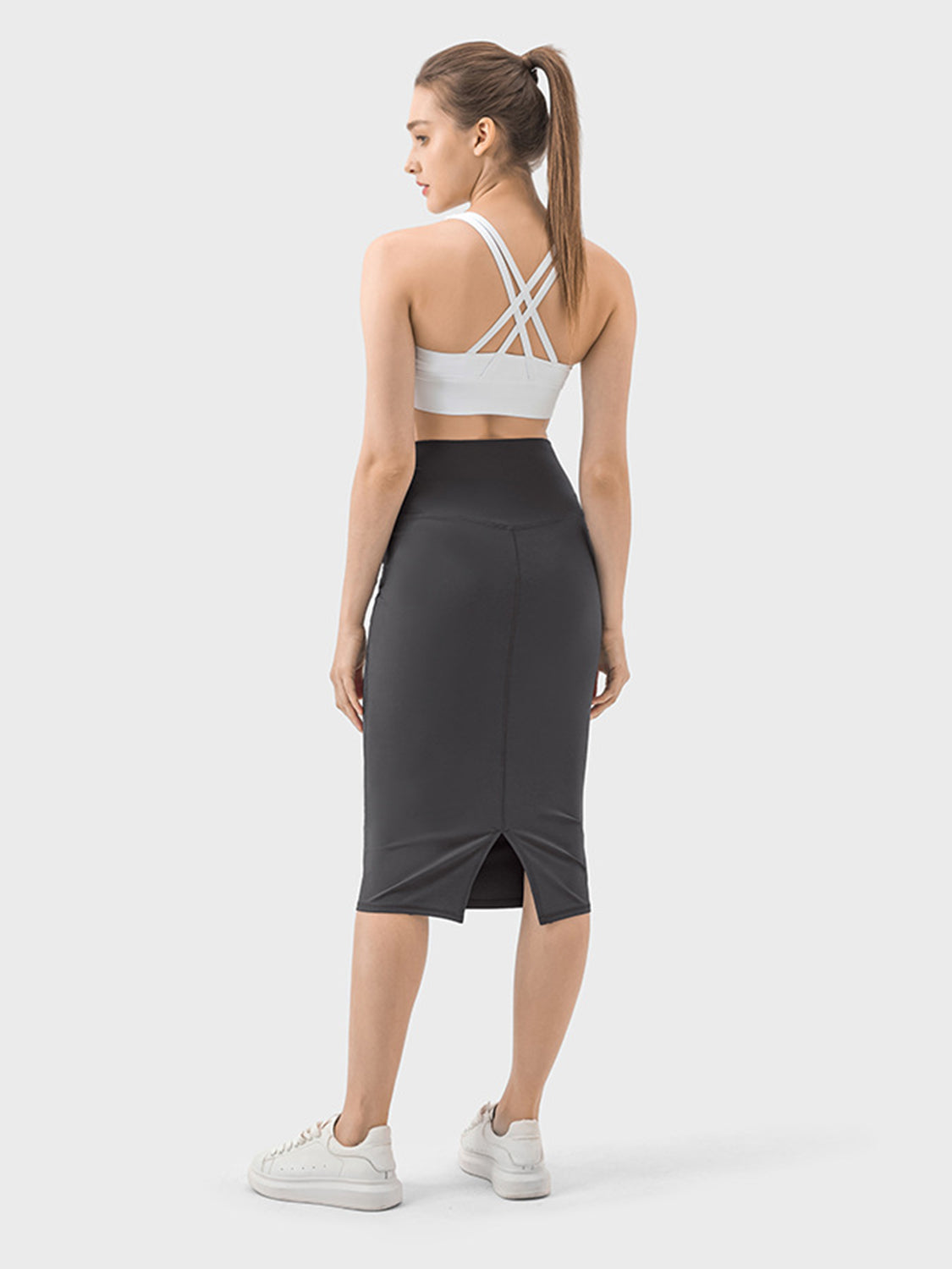 Model showcasing the Millennia Slit Wrap Active Skirt from the back, highlighting its stylish slit design and stretchy fit.