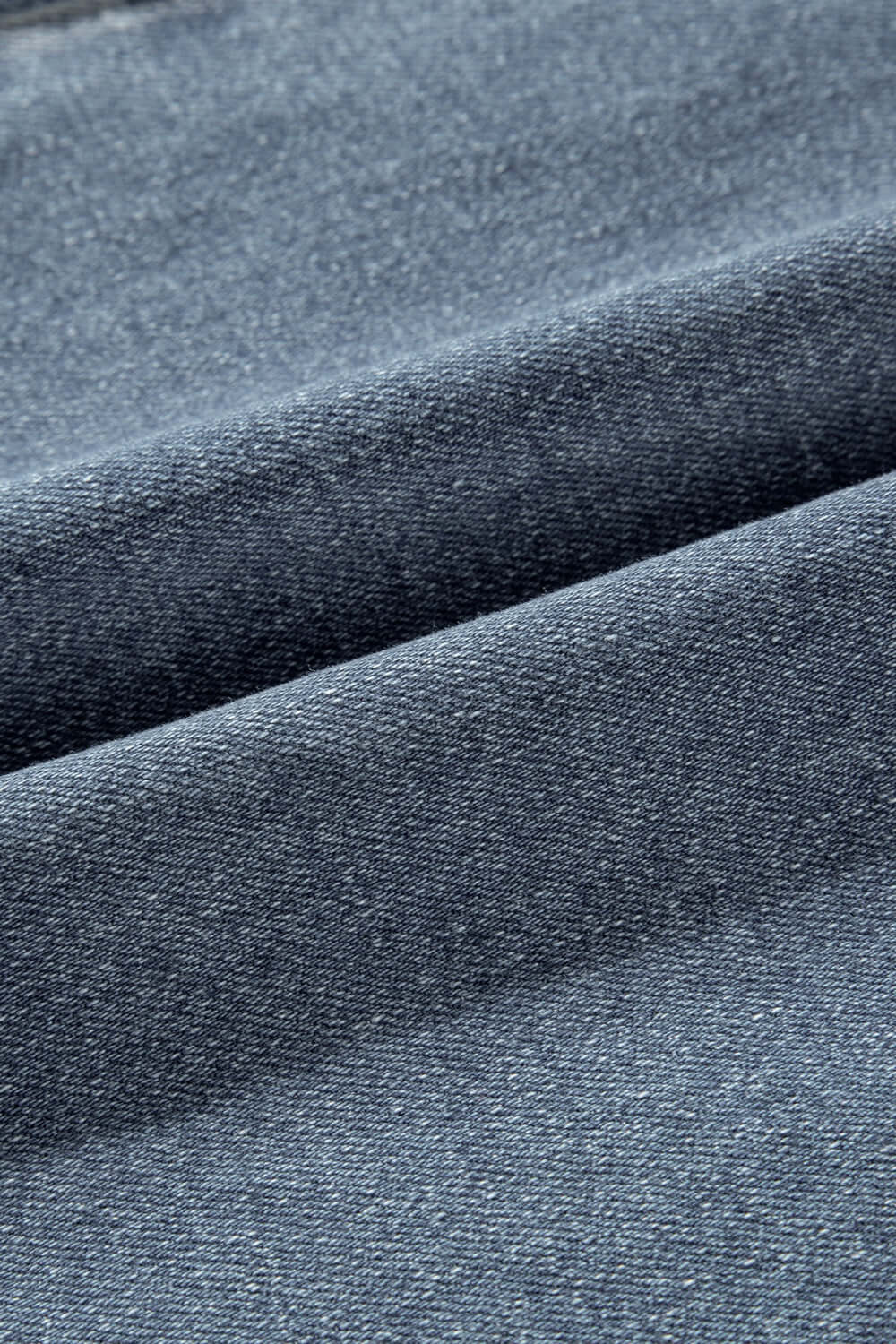 Close-up of the slightly stretchy fabric of Distressed Raw Hem Bootcut Jeans in a blend of 75% cotton, 23% polyester, and 2% elastane.