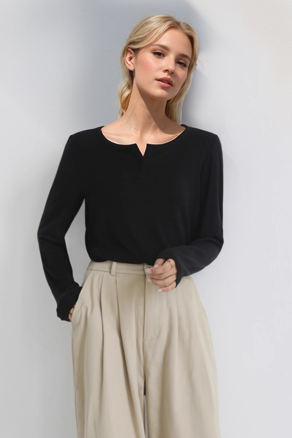 Woman in Basic Bae Notched Long Sleeve T-Shirt with beige pants, showcasing a stylish notched neckline and casual elegance.