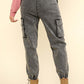 Back view of washed drawstring jogger cargo jeans with elastic waist, side pockets, and raw detail, paired with tan boots.