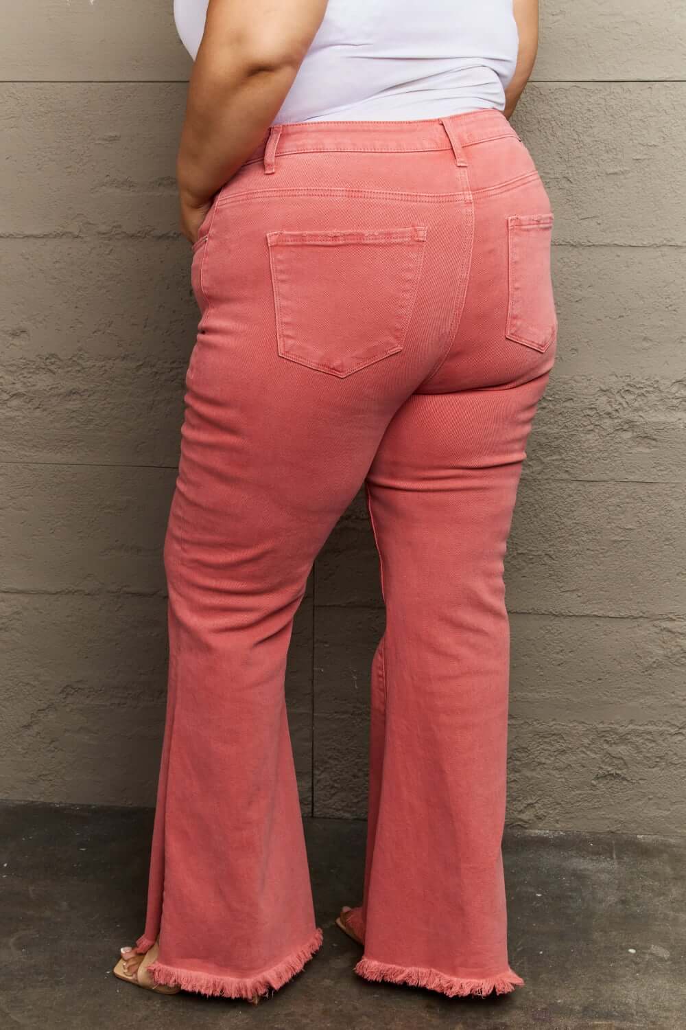 Woman wearing Bailey High Waist Side Slit Flare Jeans in pink with raw hem, showcasing stylish side slits and flattering high-rise fit.