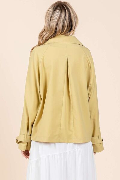 Stylish view of a woman wearing a yellow double-breasted trench coat from the back, showcasing its elegant design.