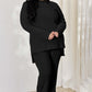 Plus-size model wearing black ribbed high-low top and wide leg pants set.