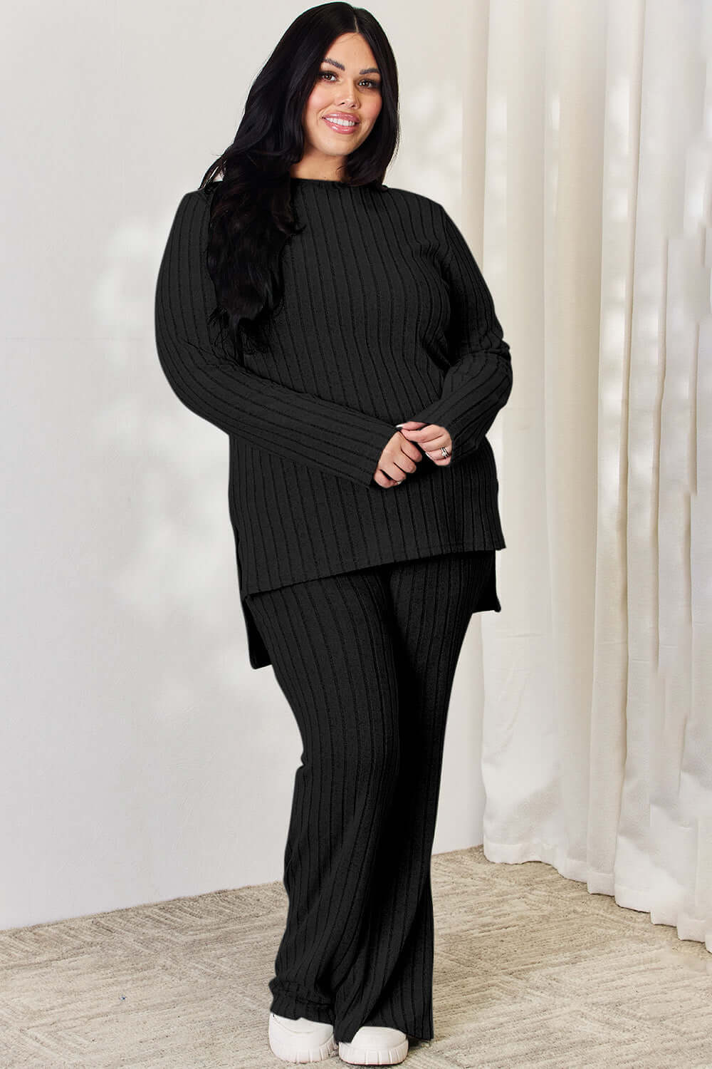 Plus-size model wearing black ribbed high-low top and wide leg pants set.