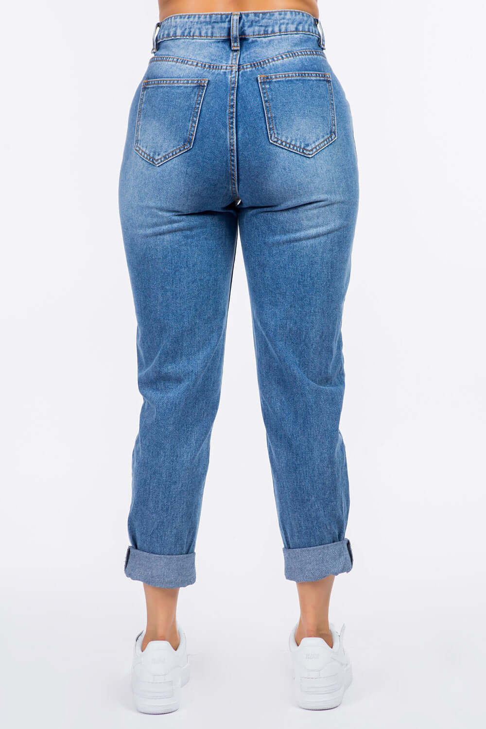 Back view of high waist pleated waist mom jeans in non-stretch denim with rolled cuffs and button closure, worn by a model with white sneakers