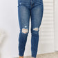 Woman wearing mid waist distressed slim jeans full size, Judy Blue Jeans, stylish denim with ripped detailing for trendy casual look.