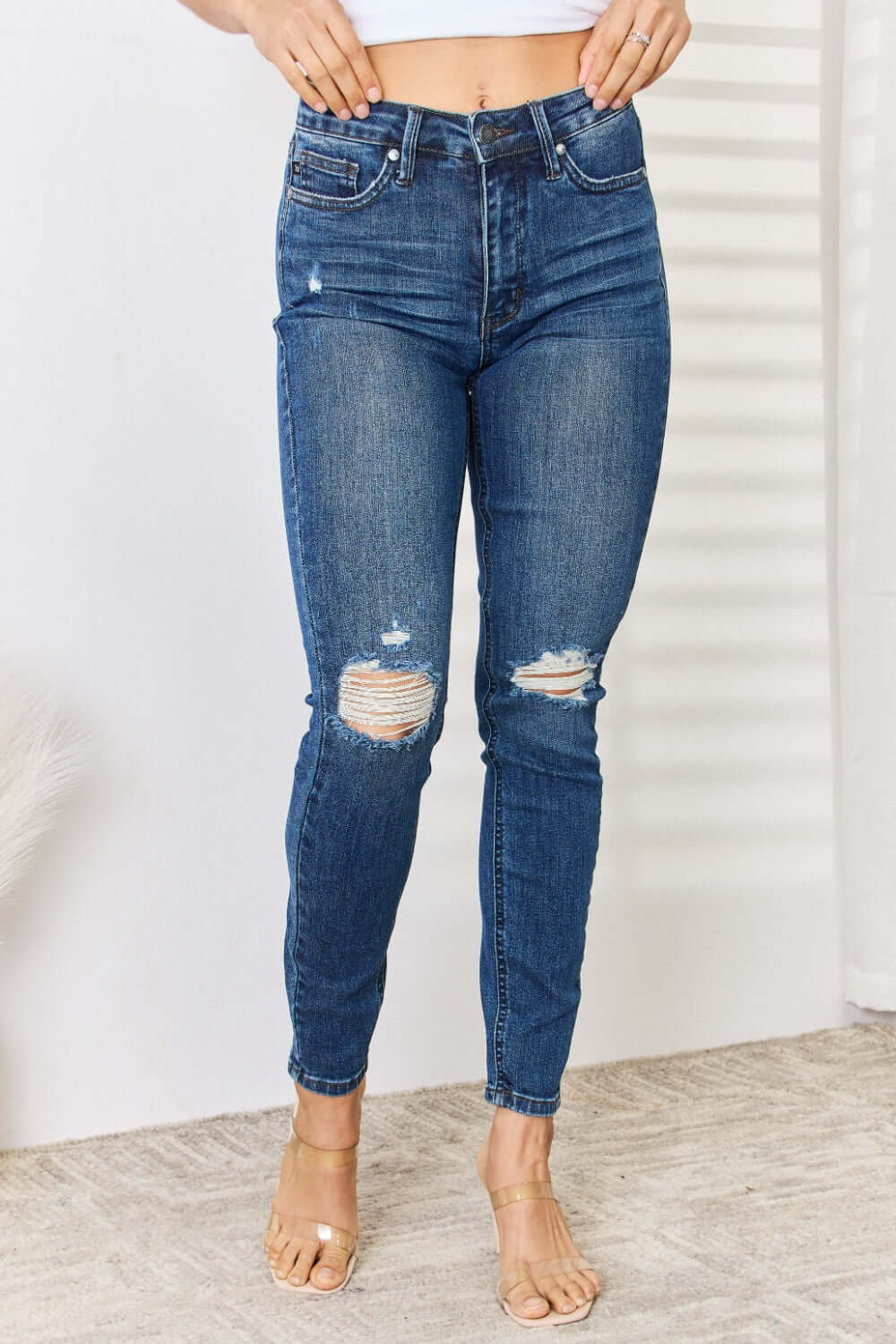 Woman wearing mid waist distressed slim jeans full size, Judy Blue Jeans, stylish denim with ripped detailing for trendy casual look.