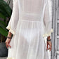 Woman wearing Fringe Tie Neck Three-Quarter Sleeve Cover Up, sheer white material with fringe details on sleeves and hem, back view.