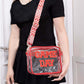 Woman holding Zenana GAME DAY transparent crossbody bag with red glitter trim and adjustable strap.