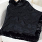 Bella Road black fuzzy hem cable-knit poncho draped on a chair, perfect for chilly days in stylish warmth.